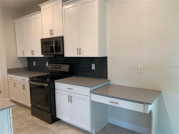 a kitchen with white cabinets and black appliances