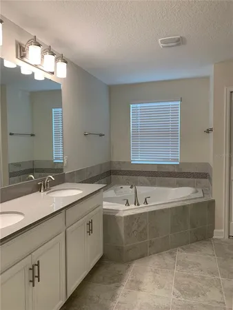 a spacious bathroom with a tub a sink and mirror
