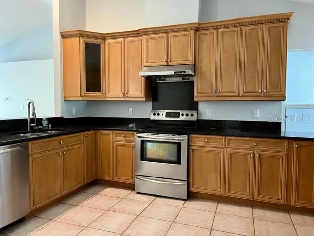 a kitchen with granite countertop a stove a sink and a microwave
