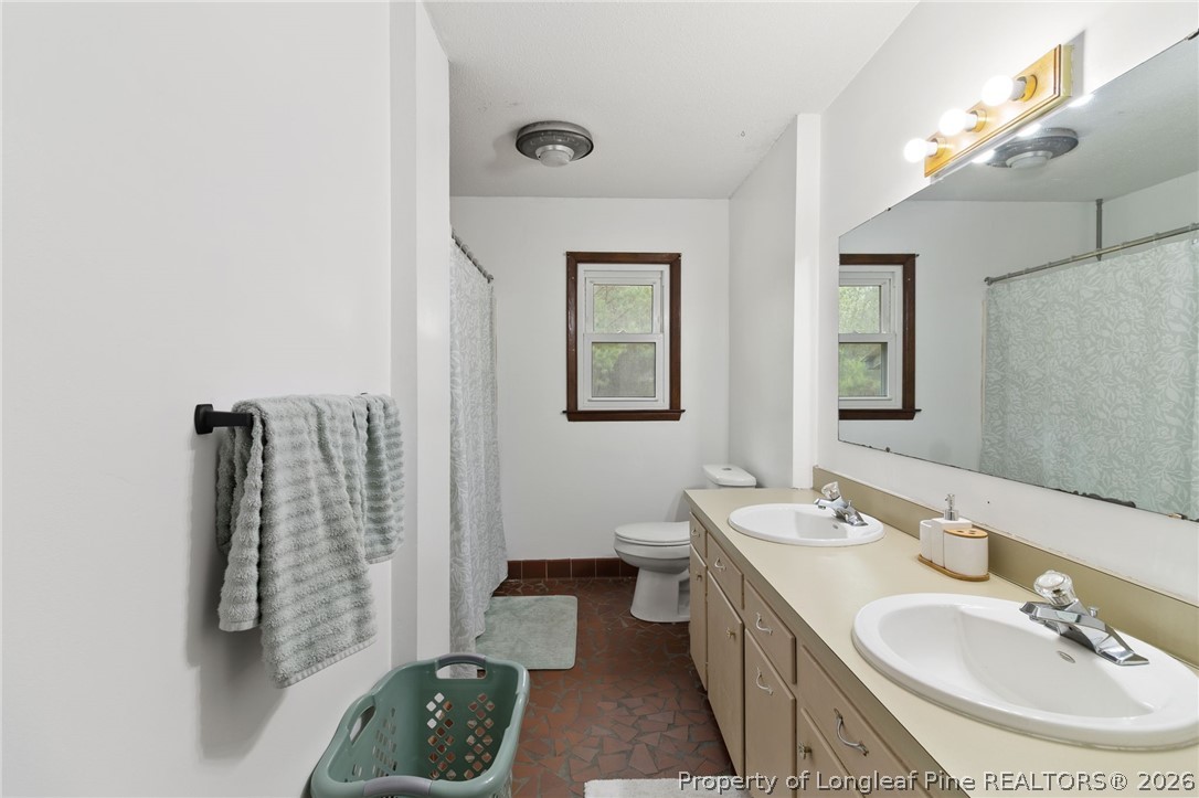 730 Slocomb Road Fayetteville, NC 28311 - Photo 28 of 48 a bathroom with a double vanity sink a mirror and a toilet