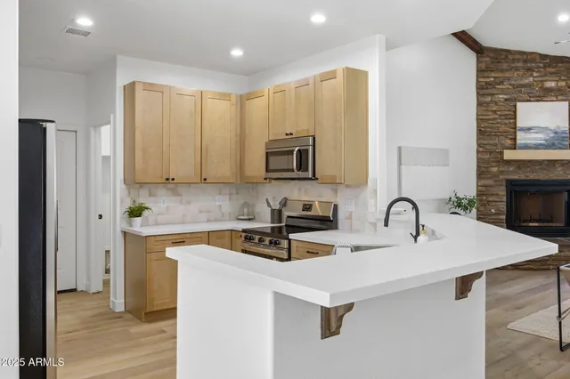 a kitchen with stainless steel appliances a stove a sink a refrigerator white cabinets and wooden floor