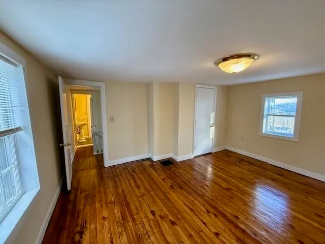 an empty room with wooden floor and windows