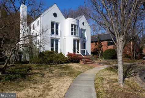 a front view of a house with garden and trees