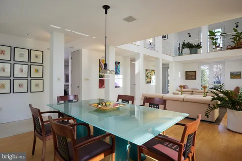 a view of a dining room and livingroom with furniture wooden floor a rug a painting and a chandelier