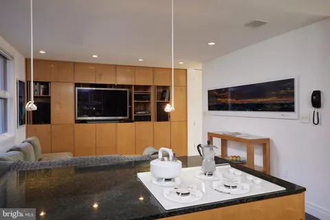 a living room with stainless steel appliances furniture a rug and a flat screen tv