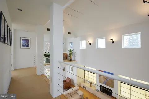 a bedroom with a bed chair and two windows