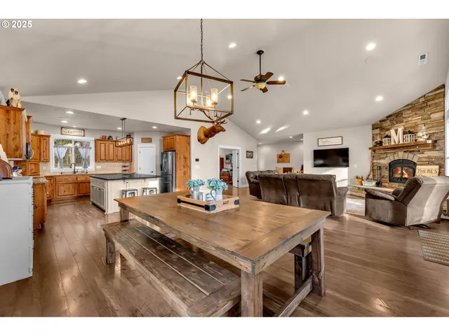 a kitchen with stainless steel appliances kitchen island granite countertop a stove a refrigerator a oven a sink a dining table and chairs with wooden floor