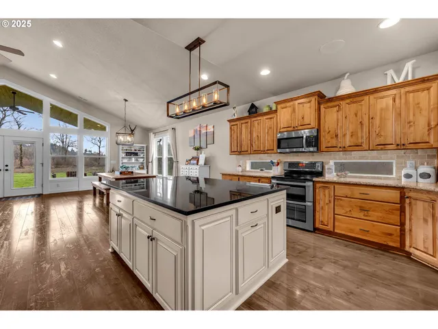 a kitchen with stainless steel appliances kitchen island granite countertop a sink stove and wooden cabinets