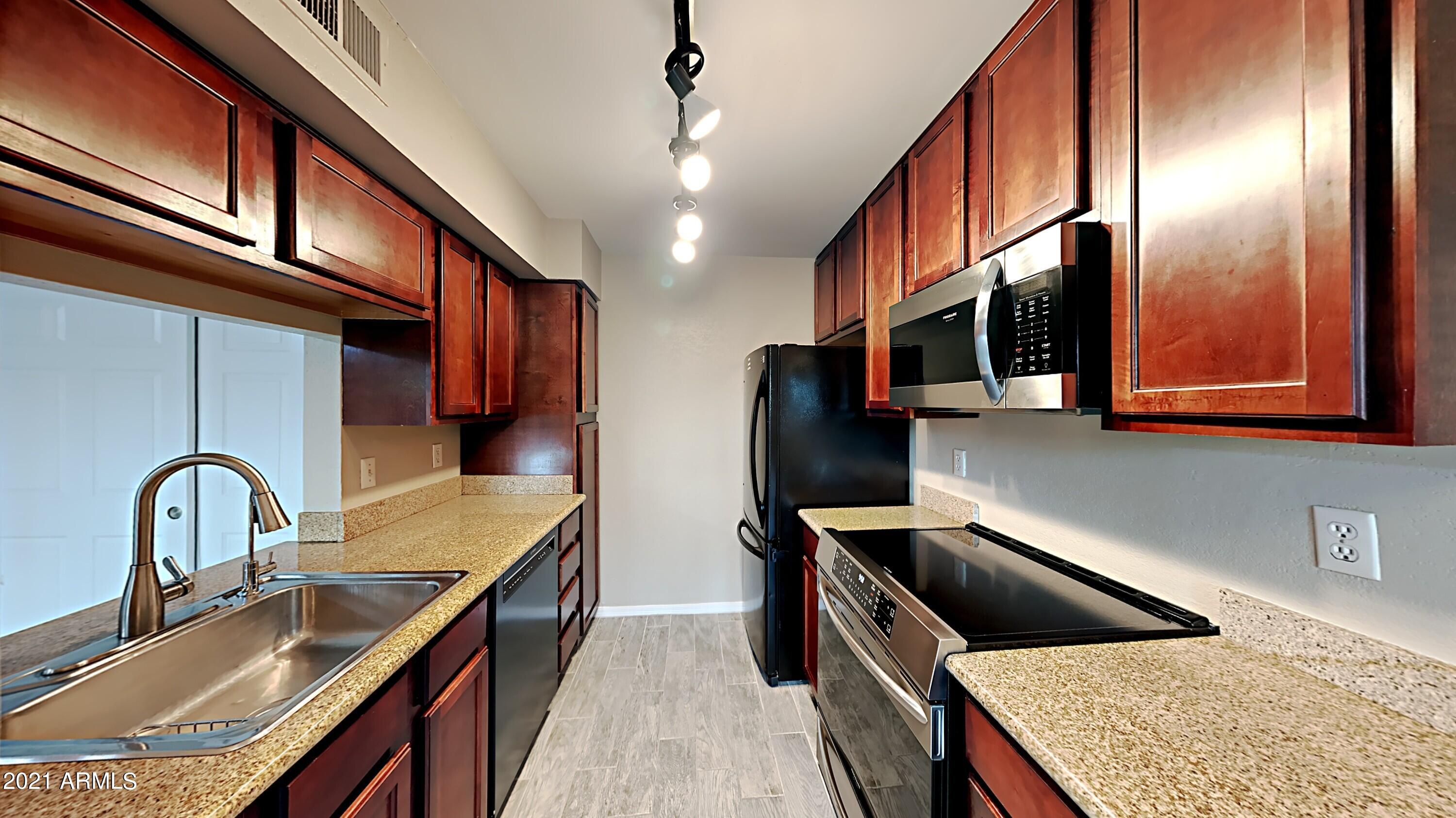 3500 North Hayden Road, Unit 1703 Scottsdale, AZ 85251 - Photo 4 of 8 a kitchen with stainless steel appliances granite countertop a sink a stove and a refrigerator with wooden cabinets