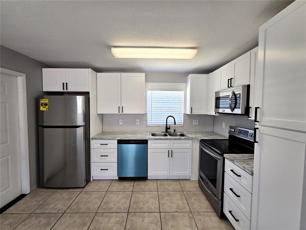 5422 Amy Lane New Port Richey, FL 34652 - Photo 10 of 25 a kitchen with stainless steel appliances granite countertop a refrigerator sink and stove