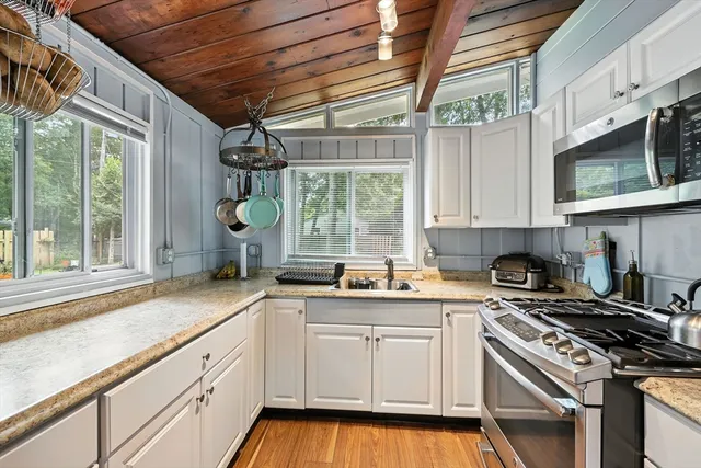 a kitchen with granite countertop white cabinets window and stainless steel appliances