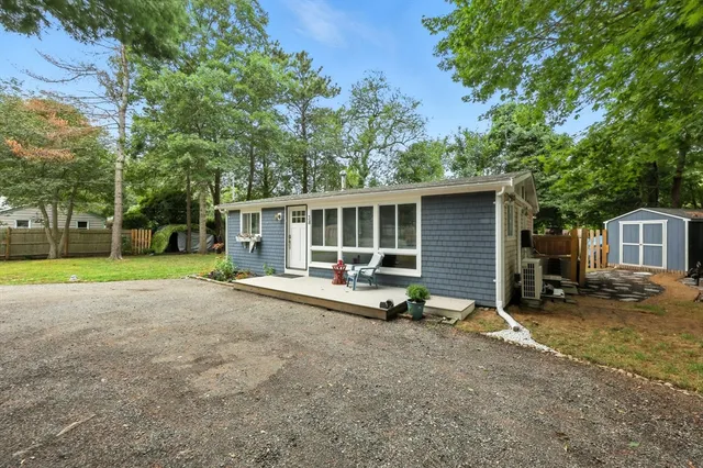 a view of a house with backyard and trees in the background
