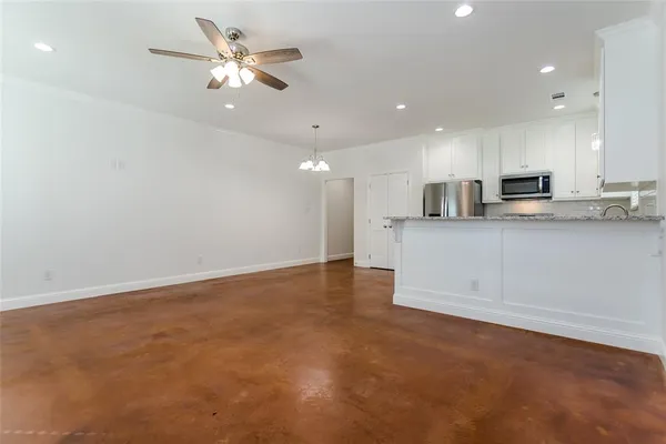 an empty room with a chandelier fan and windows