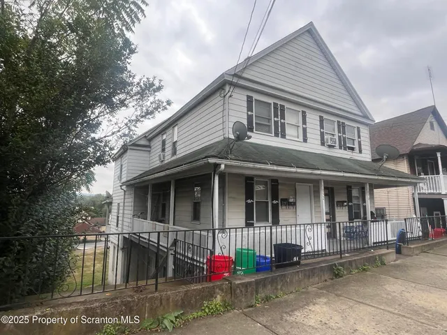 a view of small white house with large windows and a small yard