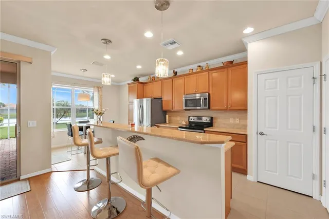 a kitchen with stainless steel appliances granite countertop a stove top oven a refrigerator a sink and a dining table with wooden floor