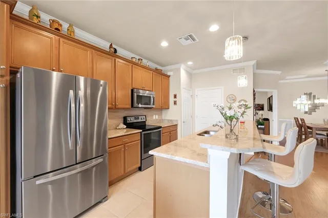 a kitchen with stainless steel appliances granite countertop a refrigerator a stove a sink a dining table and chairs with wooden floor