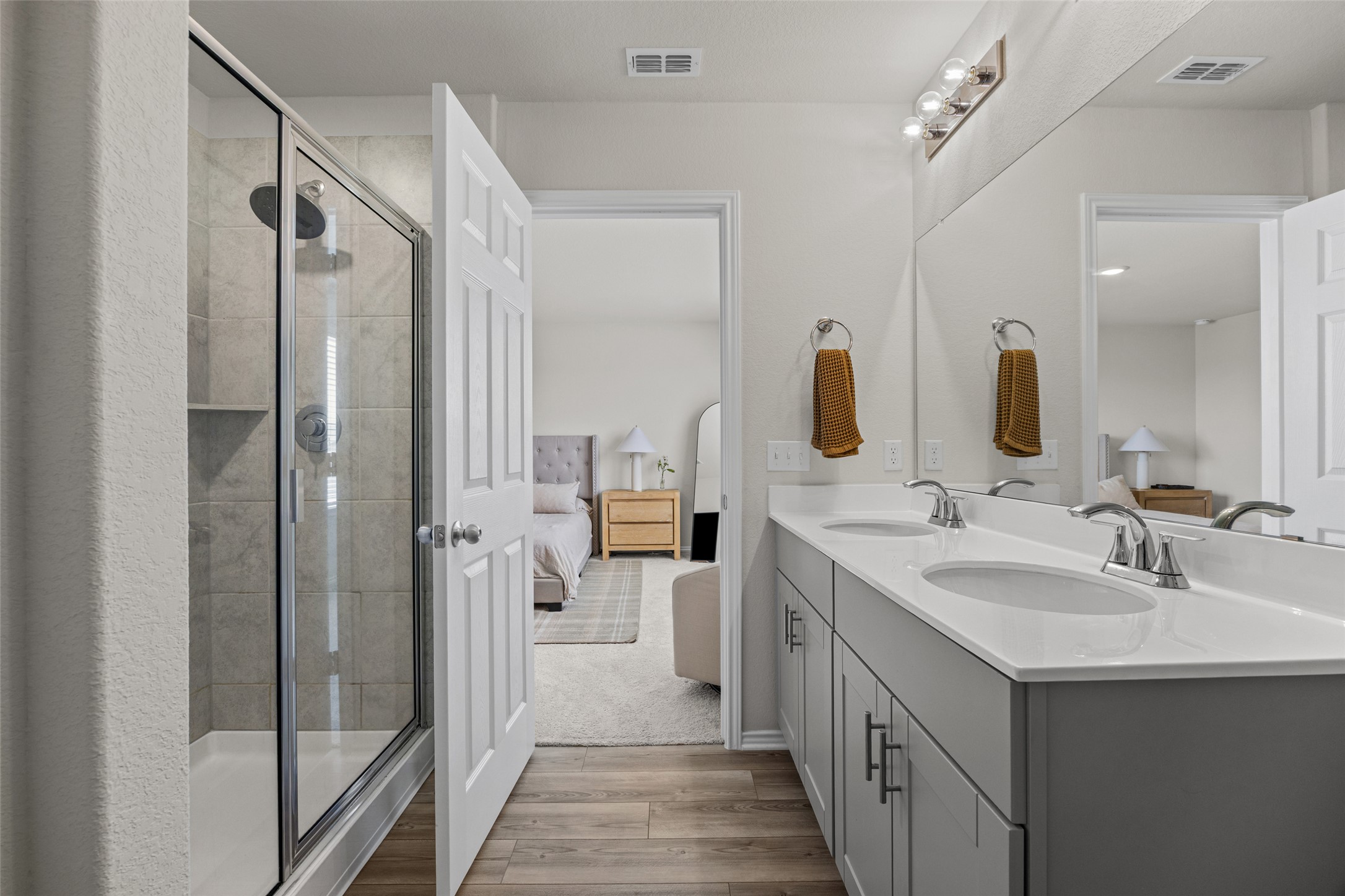 208 Orange Road Buda, TX 78610 - Photo 15 of 31 Dual vanities and a glass-enclosed shower create a practical and well-appointed primary bathroom space.