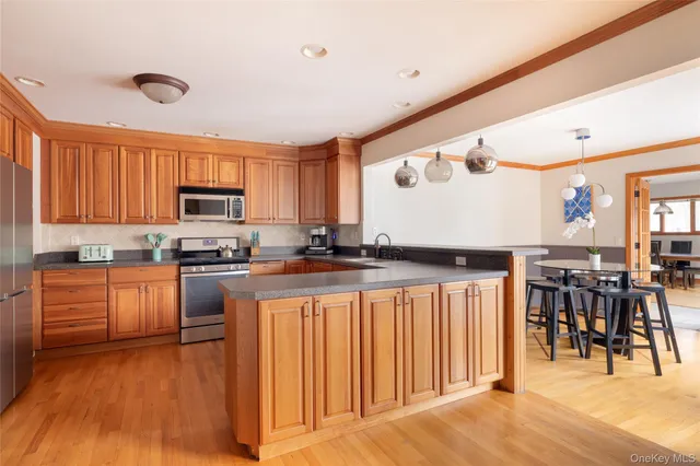 a kitchen with stainless steel appliances granite countertop a refrigerator a stove top oven a sink dishwasher and white cabinets with wooden floor