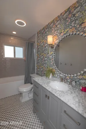 a bathroom with a granite countertop sink a toilet a mirror and bathtub