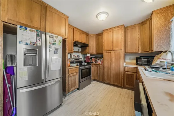 a kitchen with stainless steel appliances granite countertop a refrigerator a stove a sink dishwasher and a refrigerator with wooden floor