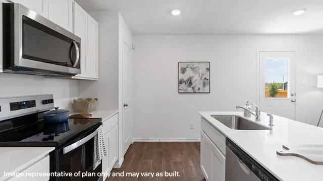 a kitchen with stainless steel appliances a sink a stove a microwave a counter top space and cabinets