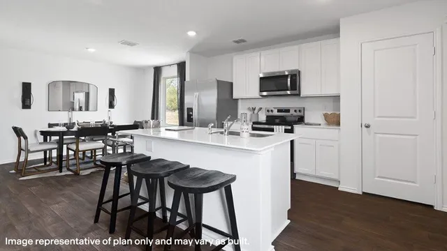 a kitchen with stainless steel appliances kitchen island granite countertop a stove a sink a dining table and chairs