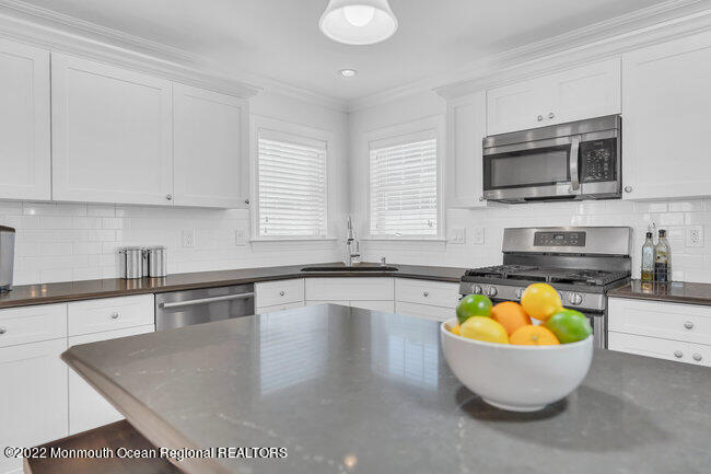 63 Fort Avenue Seaside Heights, NJ 08751 - Photo 15 of 53 a white kitchen with a sink a stove a microwave and wooden cabinets