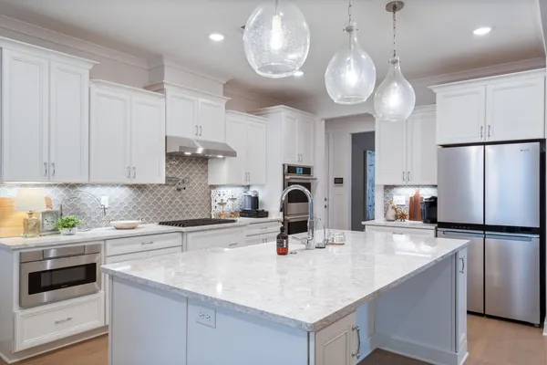 a kitchen with stainless steel appliances a sink a stove a refrigerator center island and cabinets