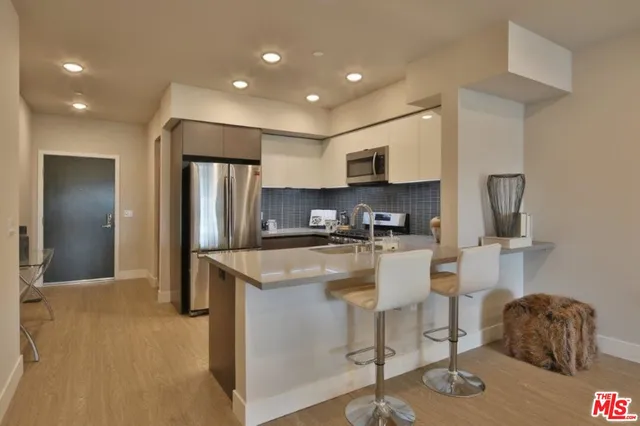 a kitchen with stainless steel appliances granite countertop a refrigerator a stove a sink a microwave a dining table and chairs