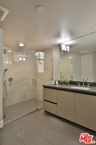 a bathroom with a mirror a double vanity sink and glass door shower