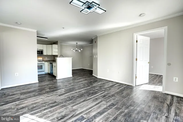 a view of empty room with wooden floor and kitchen view
