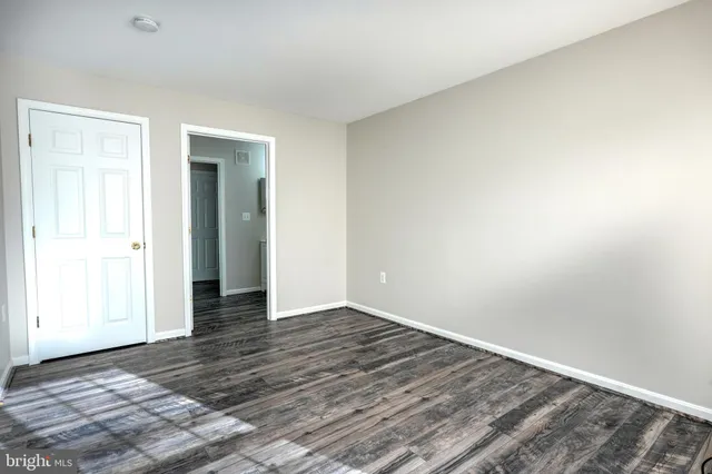 a view of an empty room with wooden floor and closet