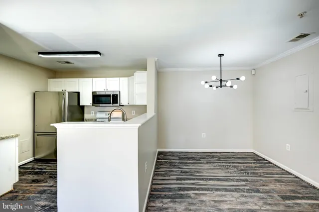 a view of kitchen and empty room with wooden floor