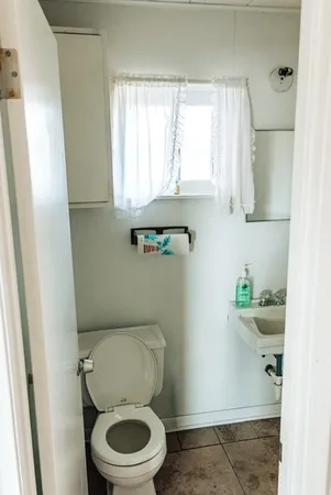 a white toilet sitting in a bathroom next to a window