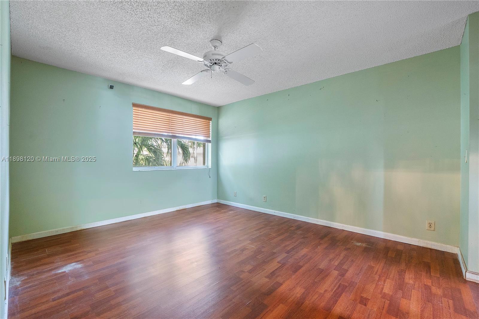 9870 Northwest 2nd Street Plantation, FL 33324 - Photo 7 of 12 an empty room with wooden floor chandelier fan and windows