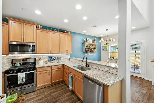 a kitchen with stainless steel appliances granite countertop a sink a stove and cabinets
