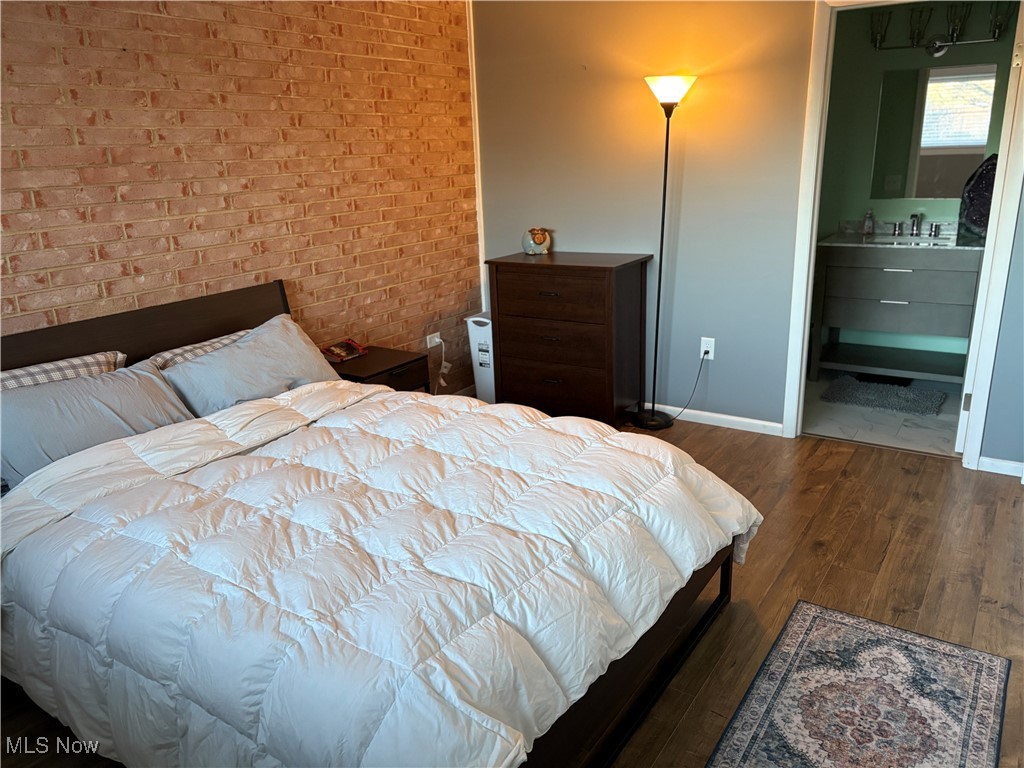 935 Canyon View Road, Unit 104 Northfield, OH 44067 - Photo 21 of 46 Bedroom featuring baseboards, wood finished floors, brick wall, and a sink