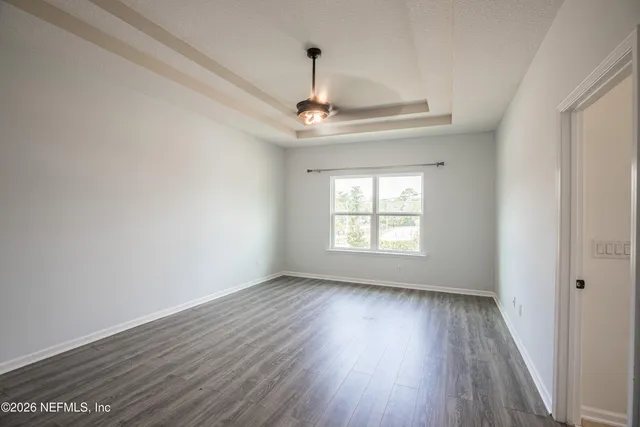 a view of empty room with wooden floor fan and window