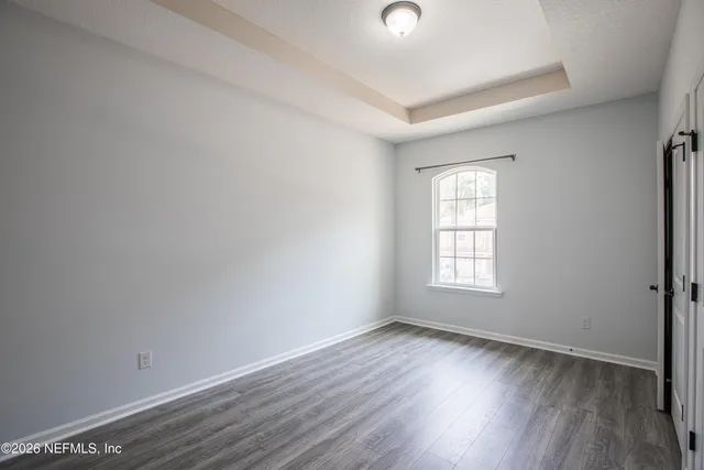an empty room with wooden floor and window