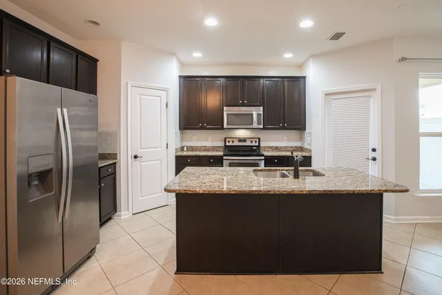 a kitchen with kitchen island stainless steel appliances a sink and a refrigerator