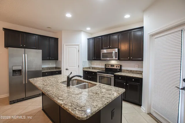 a kitchen with stainless steel appliances granite countertop a sink refrigerator and microwave