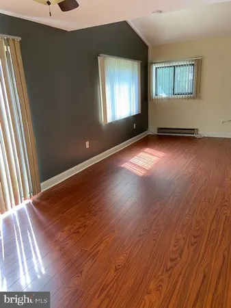 an empty room with wooden floor and windows