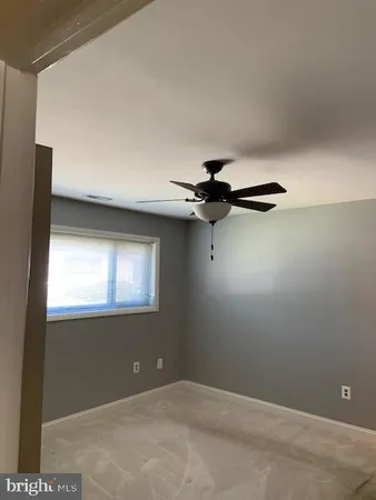 a view of an empty room with window and chandelier fan