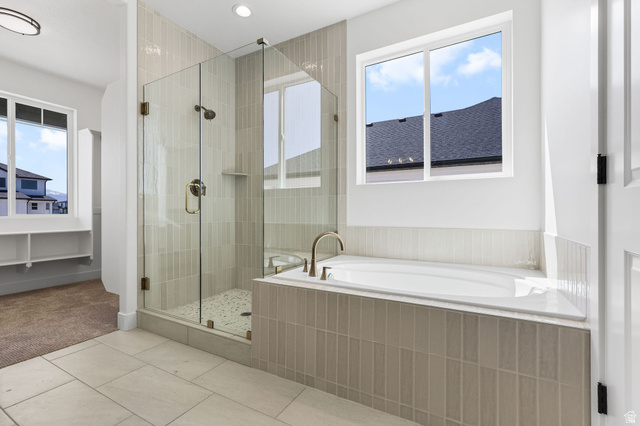 1144 South 4475 West West Point, UT 84015 - Photo 17 of 30 Spacious bathroom featuring a built-in soaking tub with a tiled surround, a glass-enclosed shower with vertical tile accents and pebble flooring, and light-toned floor tiling