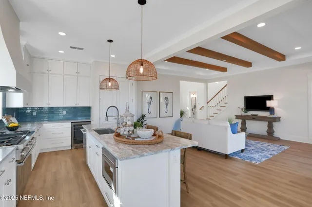 a kitchen with stainless steel appliances kitchen island granite countertop a refrigerator a stove a sink a dining table and chairs with wooden floor