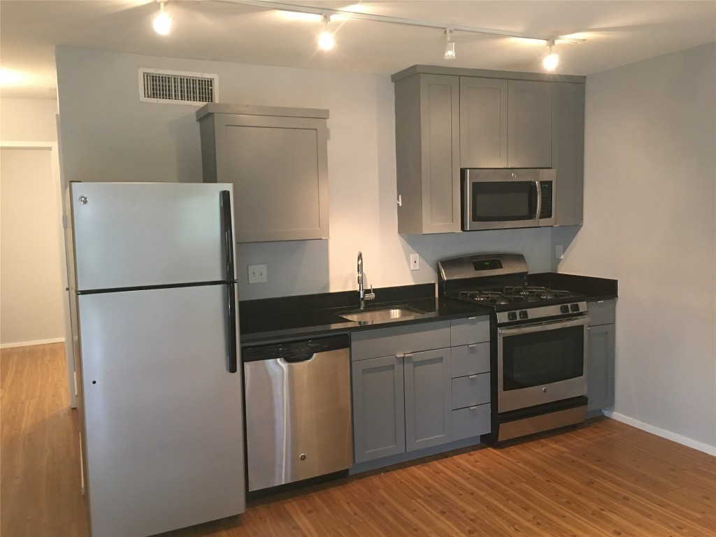 5306 Woodrow Avenue, Unit 204 Austin, TX 78756 - Photo 2 of 8 Kitchen featuring gray cabinetry, stainless steel appliances, dark countertops, and track lighting