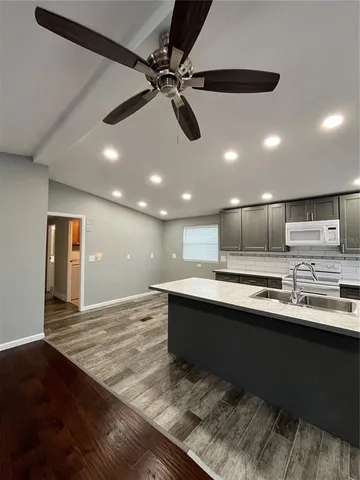 a large kitchen with stainless steel appliances a sink dishwasher a stove and a refrigerator with wooden floor