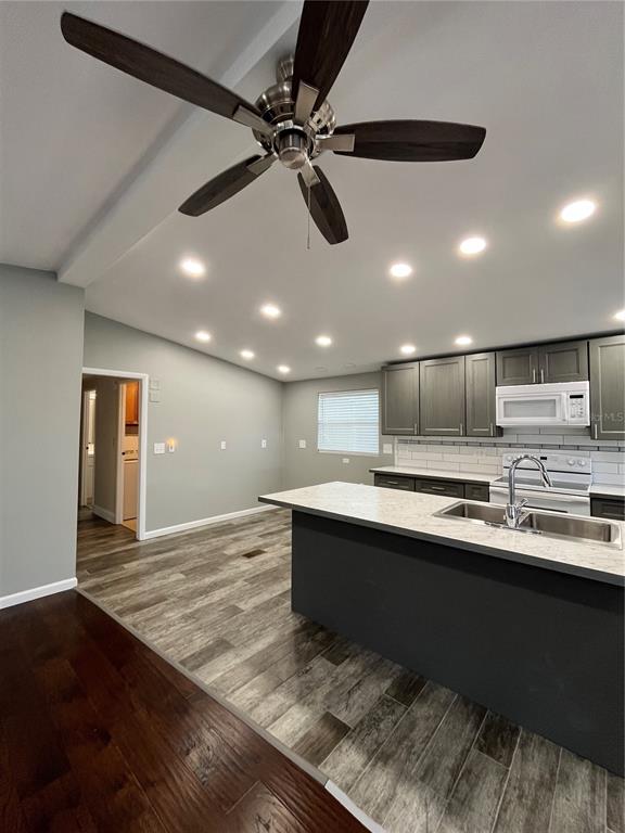 12100 Seminole Boulevard, Unit 365 Largo, FL 33778 - Photo 12 of 32 a large kitchen with stainless steel appliances a sink dishwasher a stove and a refrigerator with wooden floor