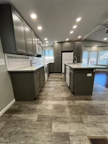 a large kitchen with kitchen island a sink wooden cabinets and stainless steel appliances