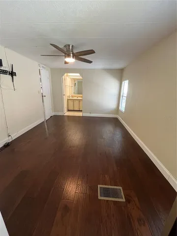 an empty room with wooden floor fan and windows